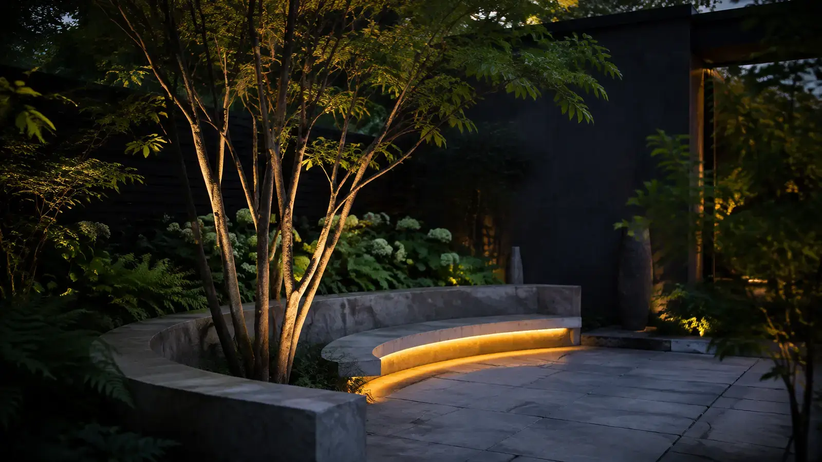 Intimate garden terrace with curved stone seating and mature planting